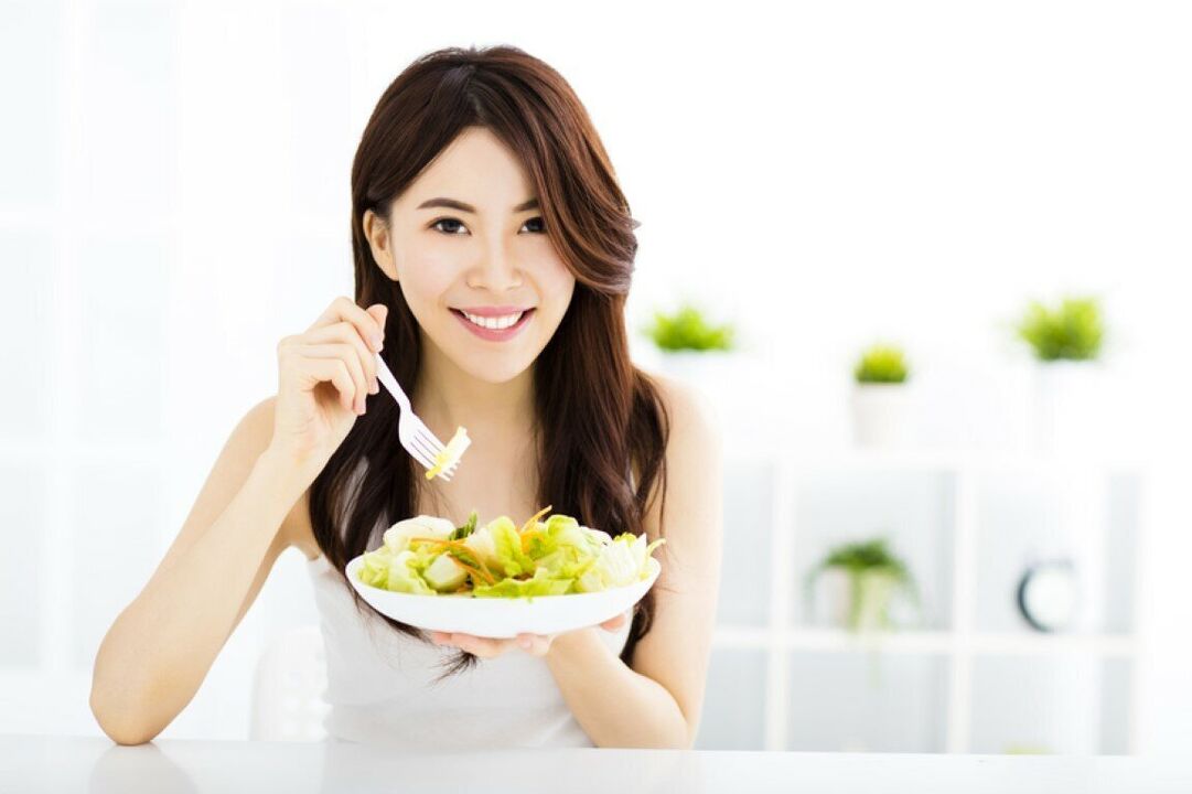 Die japanische Frau isst einen Salat